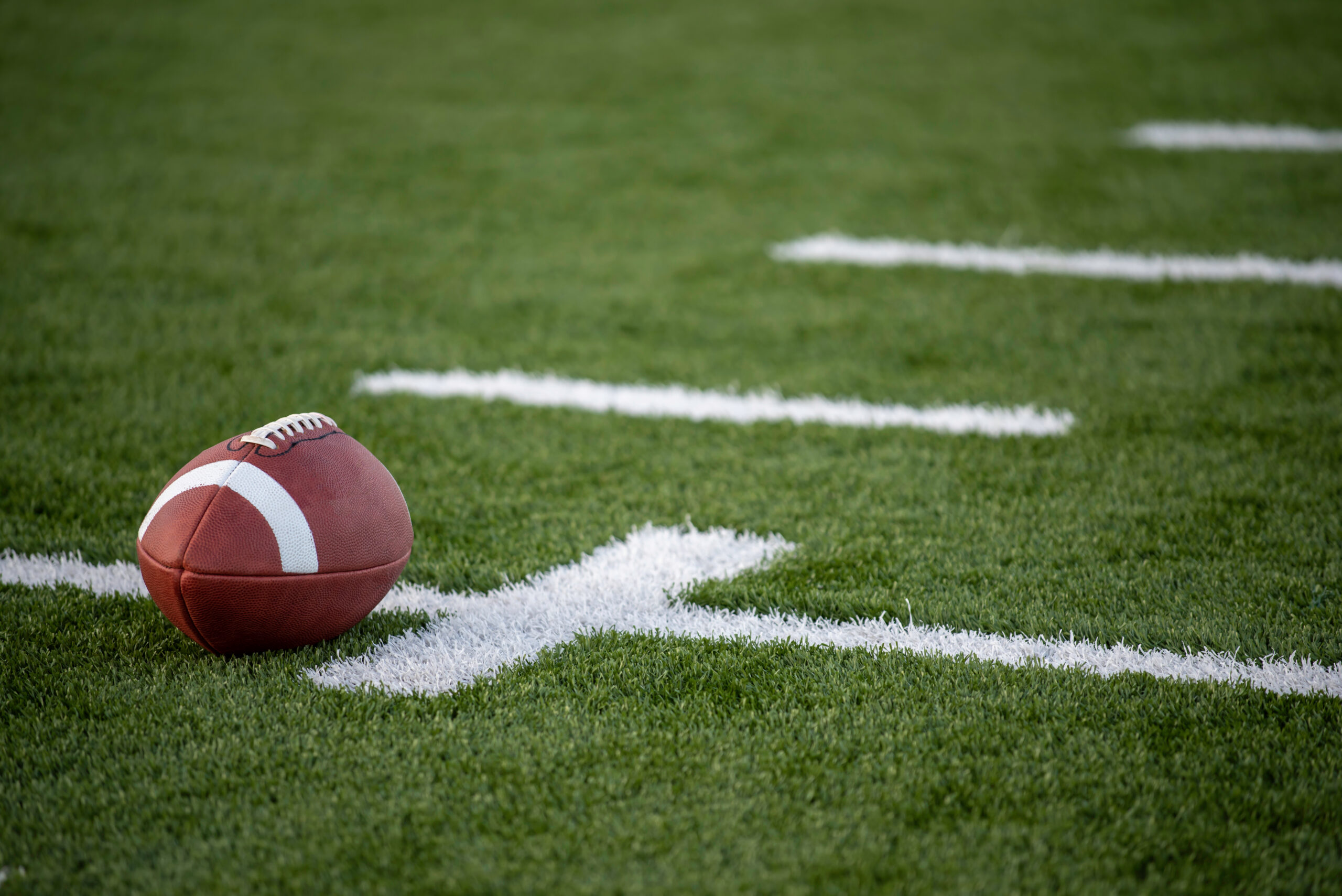 A brown leather american football on a green playing field